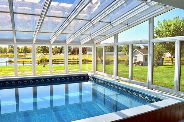 A secluded luxury pool conservatory with ornate iron frames and frosted glass privacy panels