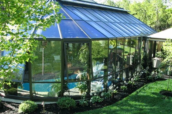 A bright pool conservatory in spring with lush greenery visible through glass panels